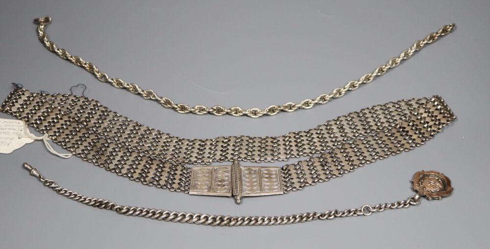 An Indian white metal belt and two alberts including silver and a silver and yellow metal medallion.